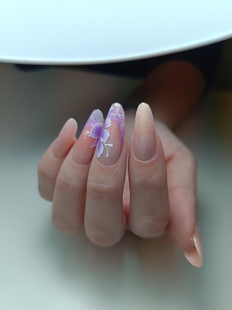 Nail art fleurs violettes avec paillettes sur ongles en gel – formation prothésiste ongulaire à Basse-Goulaine Nantes